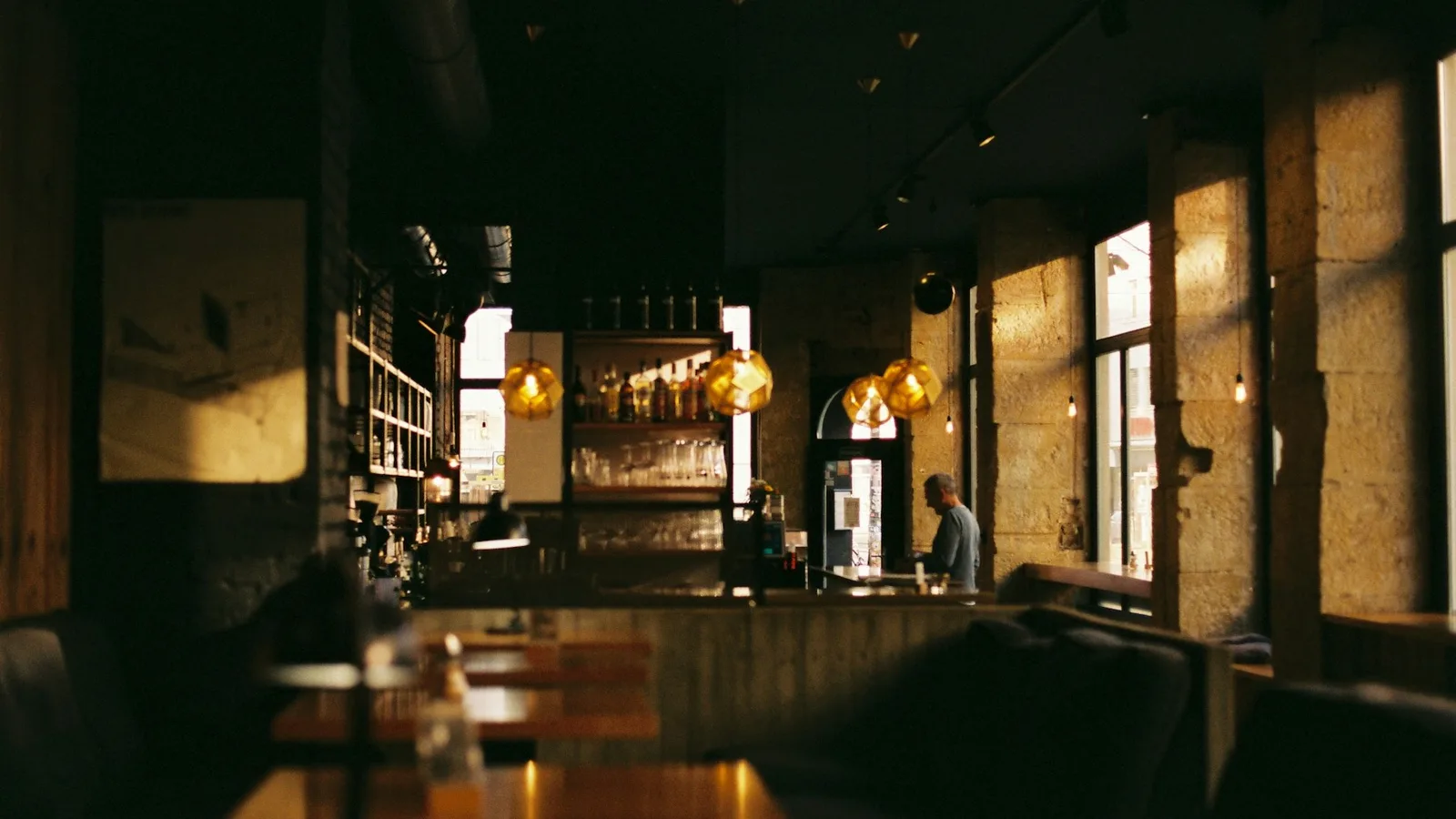 Dark restaurant dining room with golden lamps in the evening (photo Oliver Guhr / Unsplash)