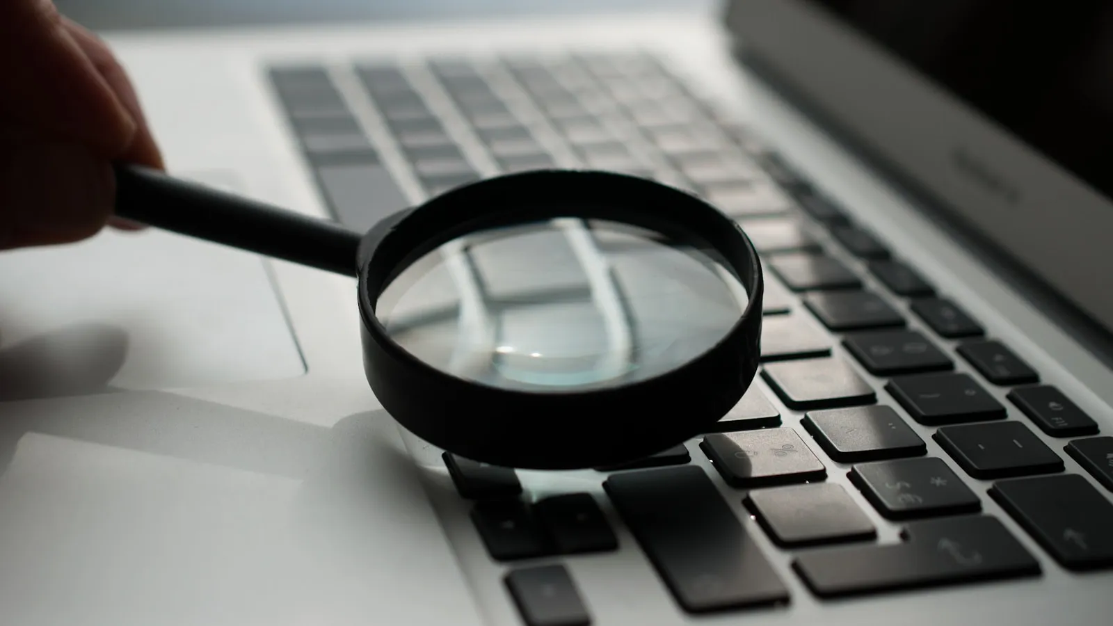Magnifying glass next to a laptop — SEO and Google Ads compared (photo Agence Olloweb / Unsplash)