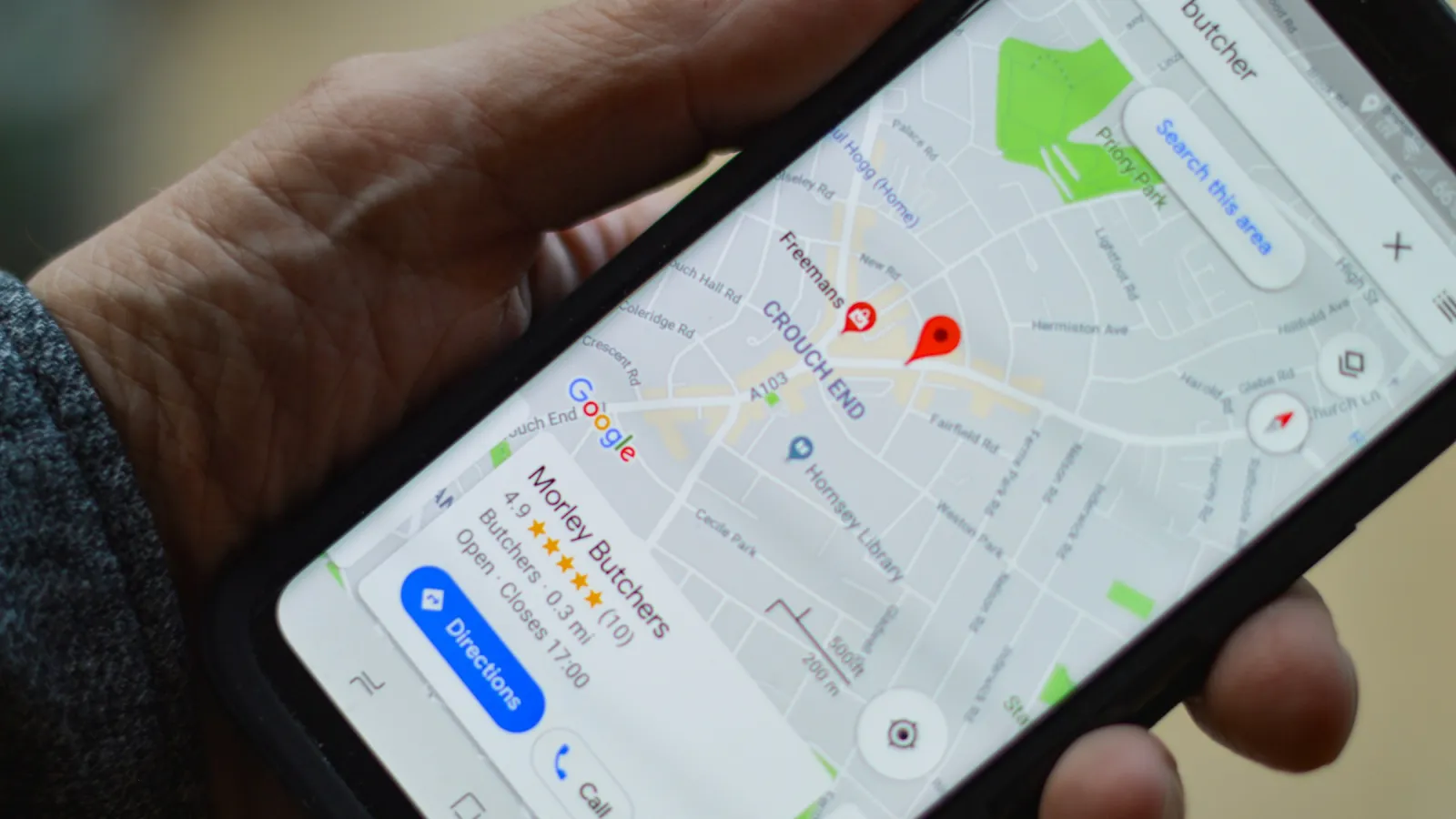 Hand holding a smartphone with Google Maps open — searching for a local business